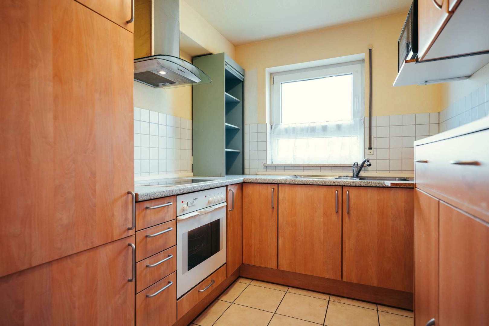 Küche mit Herd, Backofen, Kühlschrank, Arbeitsfläche und Schränken