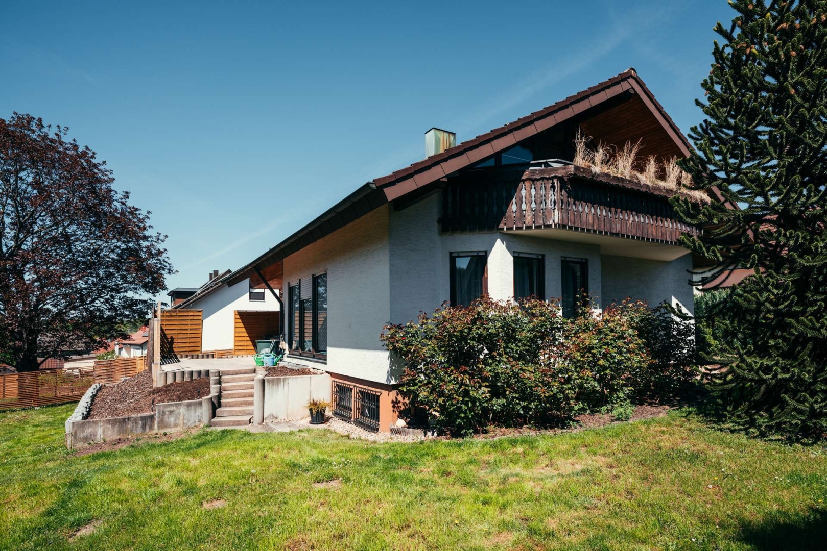 Sonnige Gartenansicht mit Balkon
